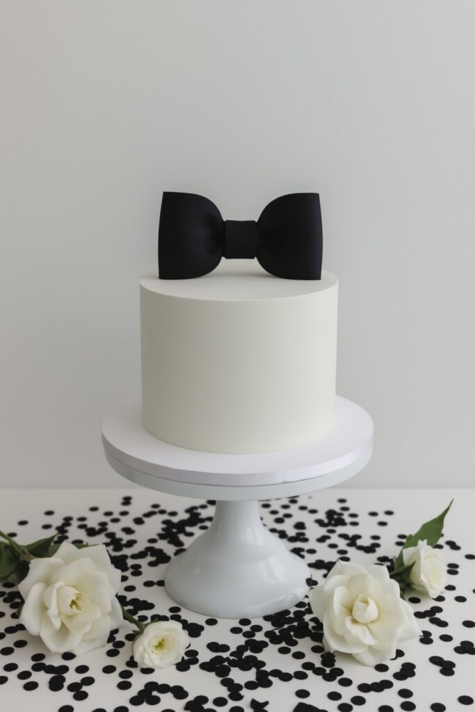 Minimalist White Cake With Black Bow Topper
